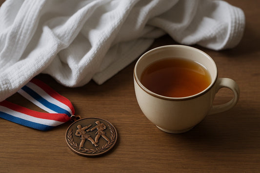 A cup of tea beside a karate tournament medal and a rumpled gi.