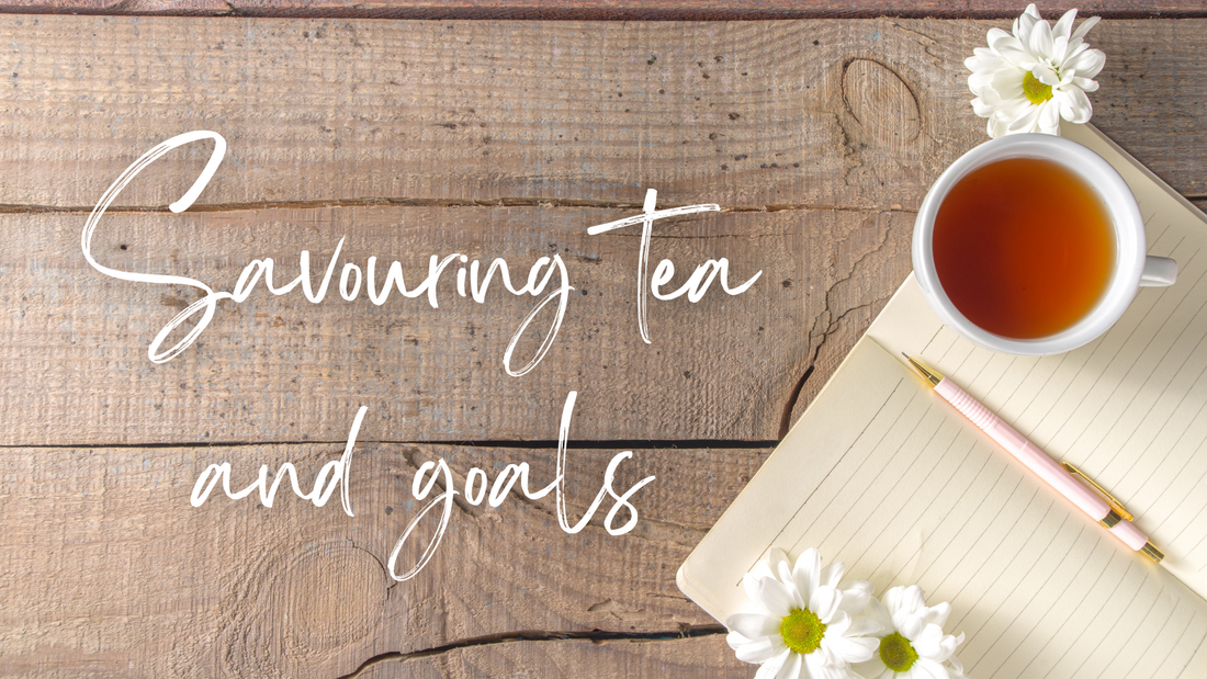Savouring Tea and Goals - a notebook and cup of tea on a wood table with daisies