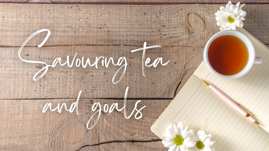 Savouring Tea and Goals - a notebook and cup of tea on a wood table with daisies