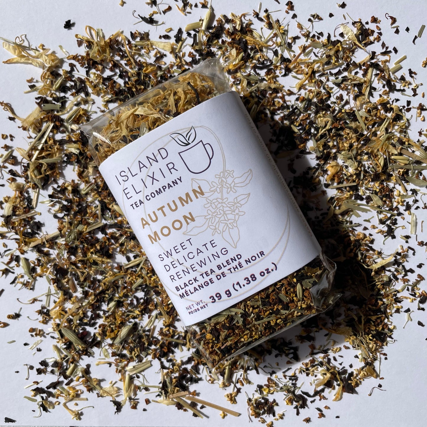 Tea package from Island Elixir Tea Company Autumn Moon black tea blend in 'Essential' size surrounded by scattered tea