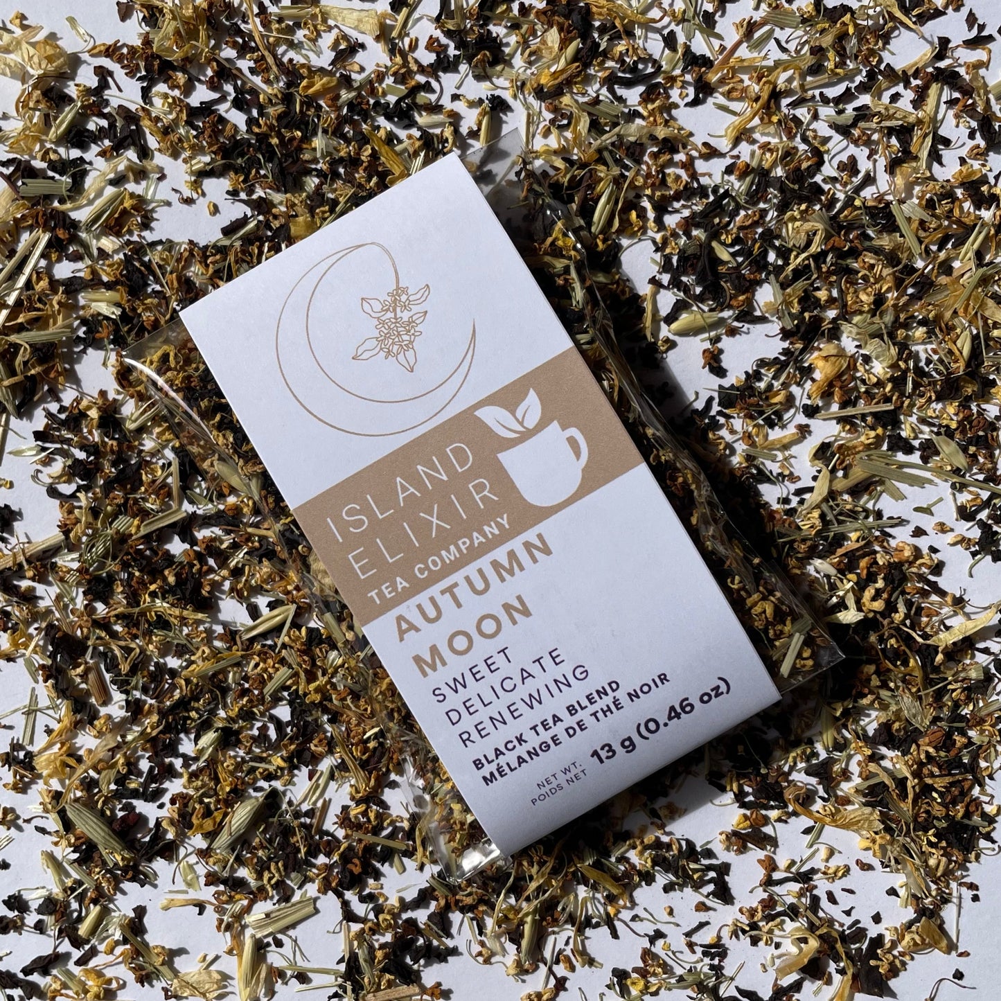 Tea package from Island Elixir Tea Company Autumn Moon black tea blend in 'Savour' size surrounded by scattered tea