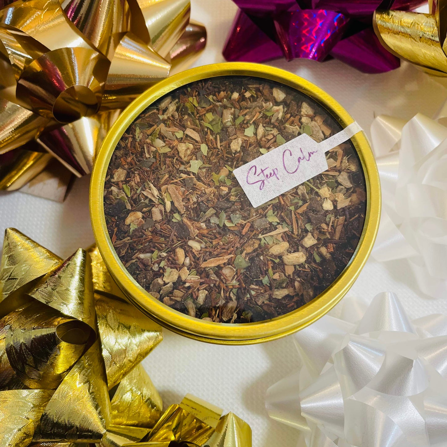 Gold tin of loose leaf tea with decorative bows in the background