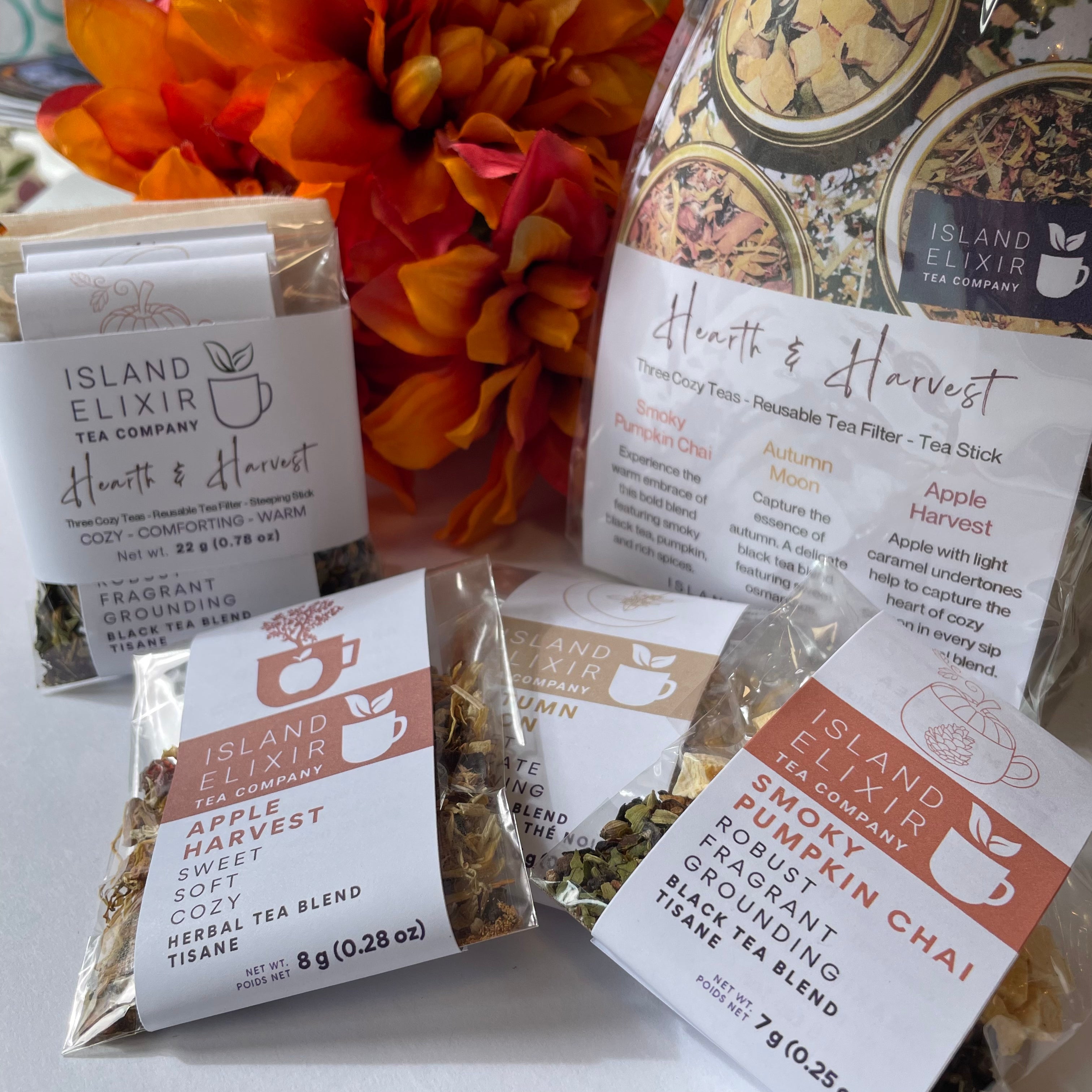 In the foreground a collection of teas for fall showing Apple Harvest, Autumn Moon, Smoky Pumpkin Chai in 'Discover' size. In the background Hearth and Harvest Tea Trios in Discover and Savour sizes.