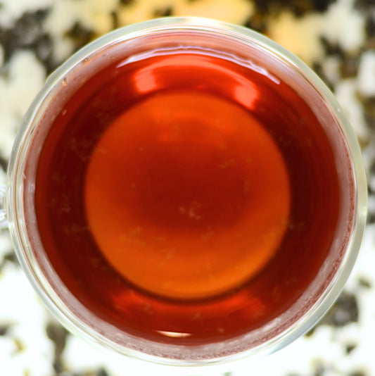 Summit Tea Brewed. Summit organic black tea shown steeped in a clear glass cup. The tea is a lively and deep burgundy colour that reflects the WOW factor of the high-grown, high elevation tea from Nepal.