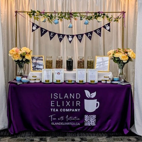 Island Elixir Tea Company's Serene Tea Bar setup with loose leaf teas, tea information signs, smelling tins, and beautiful tea-themed flower arch.