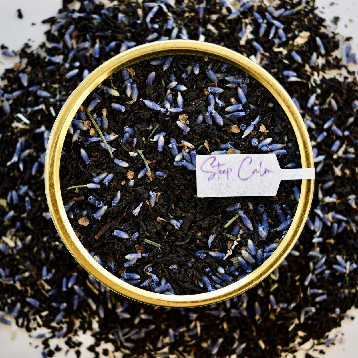 The Earl's Lover Black Tea 30 cups of tea size gold finish tin sitting on loose leaf tea that contains Black tea*, lavender**, anise hyssop*, bergamot flavour (organic compliant)