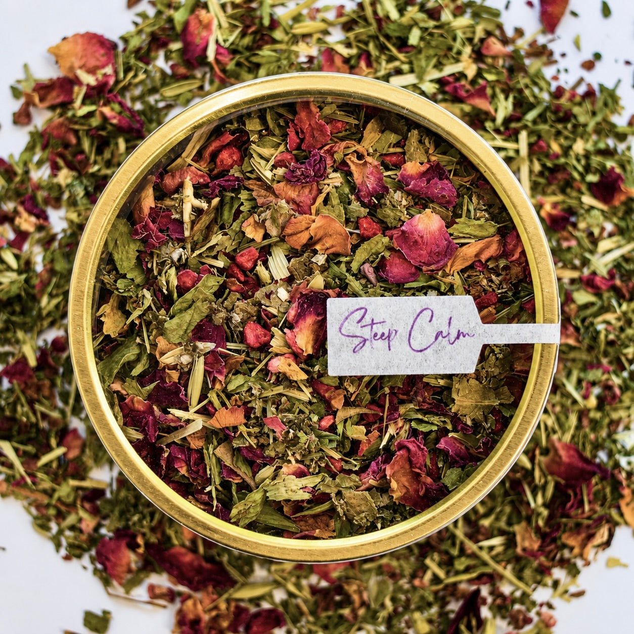 Time out Herbal Tea 30 cups of tea size gold finish tin sitting on loose leaf tea that contains Raspberry, Alfalfa, Oatstraw, Rose, Rooibos, Nettle, Red clover, Raspberry leaf