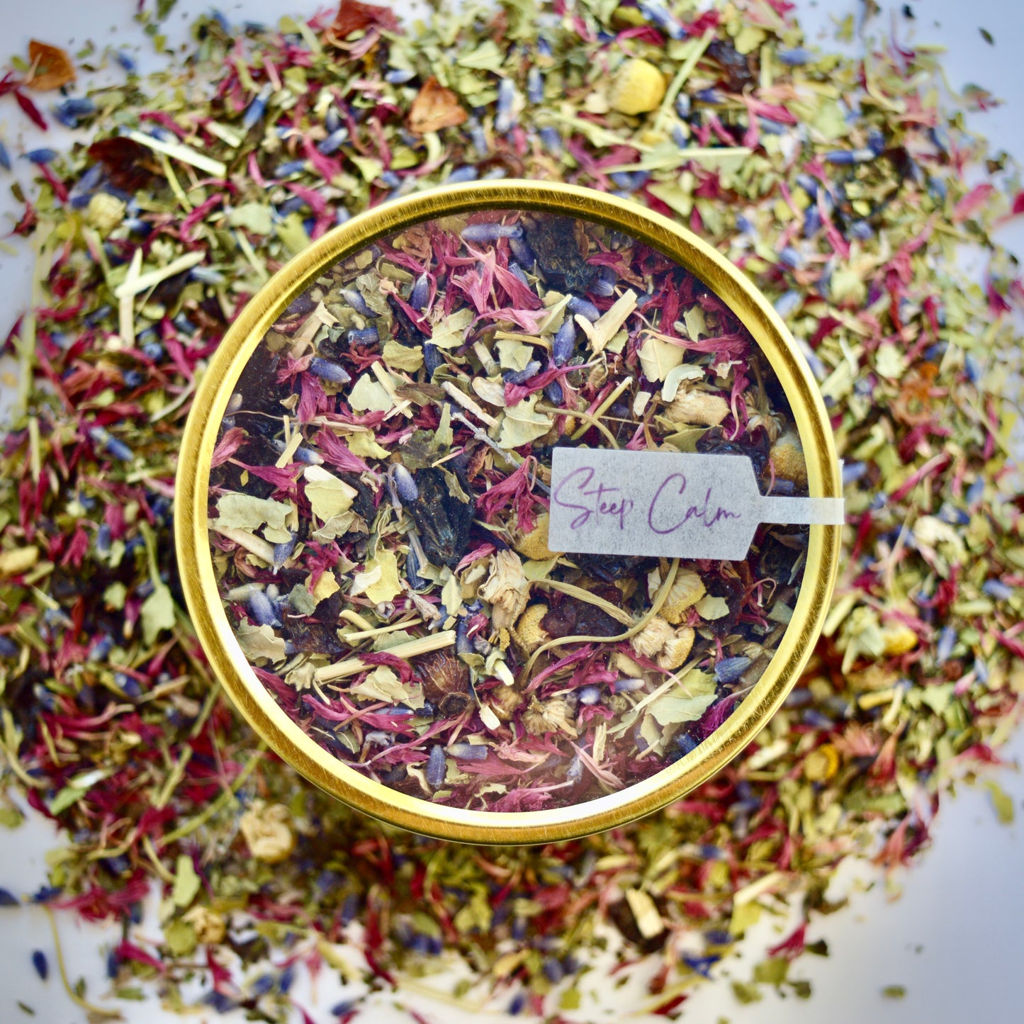 West Coast Unwind Herbal Tea 30 cups of tea size gold finish tin sitting on loose leaf tea that contains rose hip, lemon balm, lavender, marshmallow leaf, passion flower chamomile, red cornflower.
