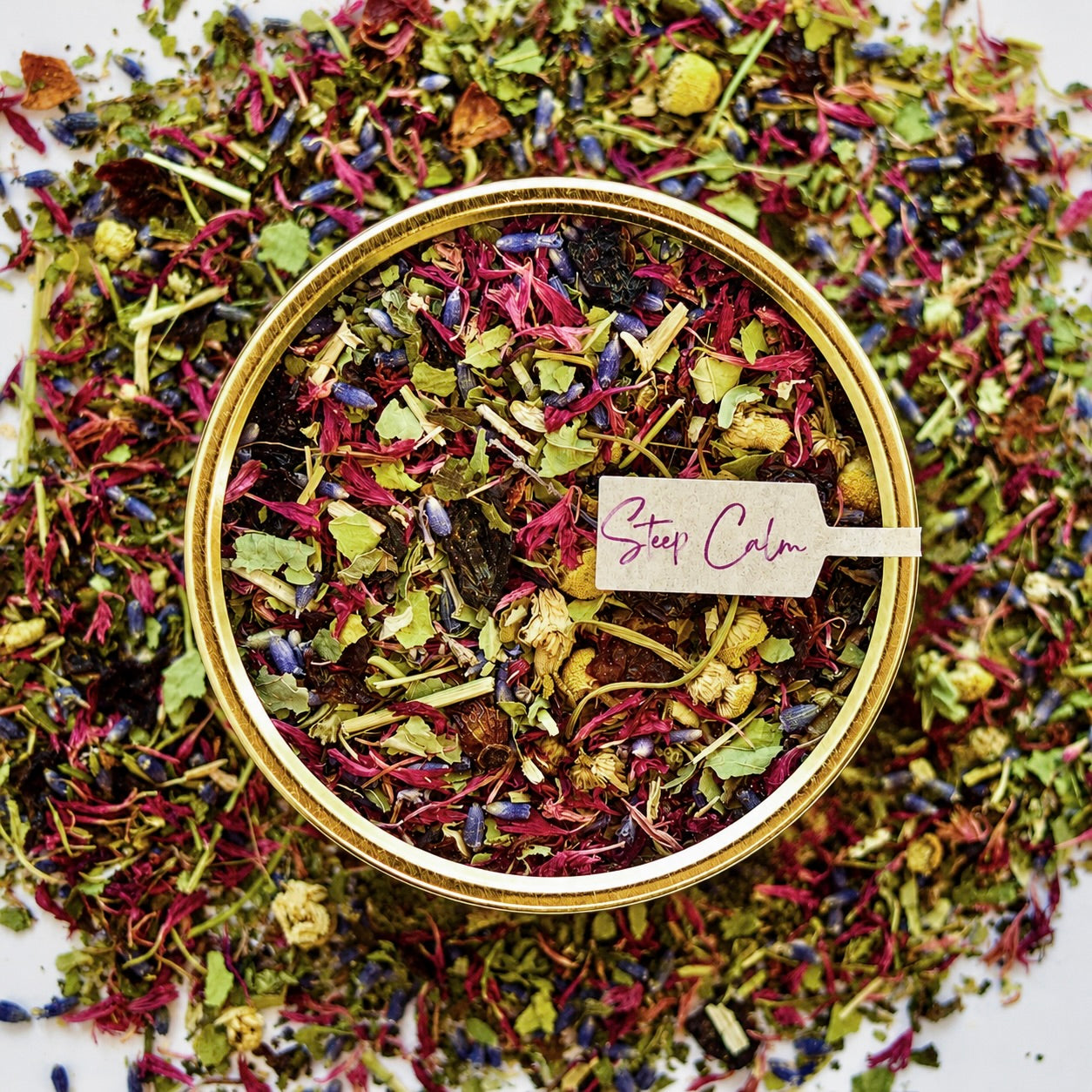 West Coast Unwind Herbal Tea 30 cups of tea size gold finish tin sitting on loose leaf tea that contains rose hip, lemon balm, lavender, marshmallow leaf, passion flower chamomile, red cornflower.
