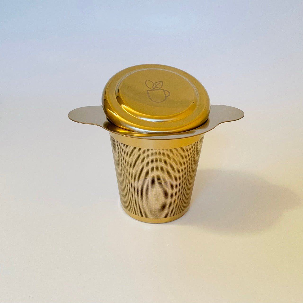 Island Elixir's gold finish tea infuser with lid pictured on a white background