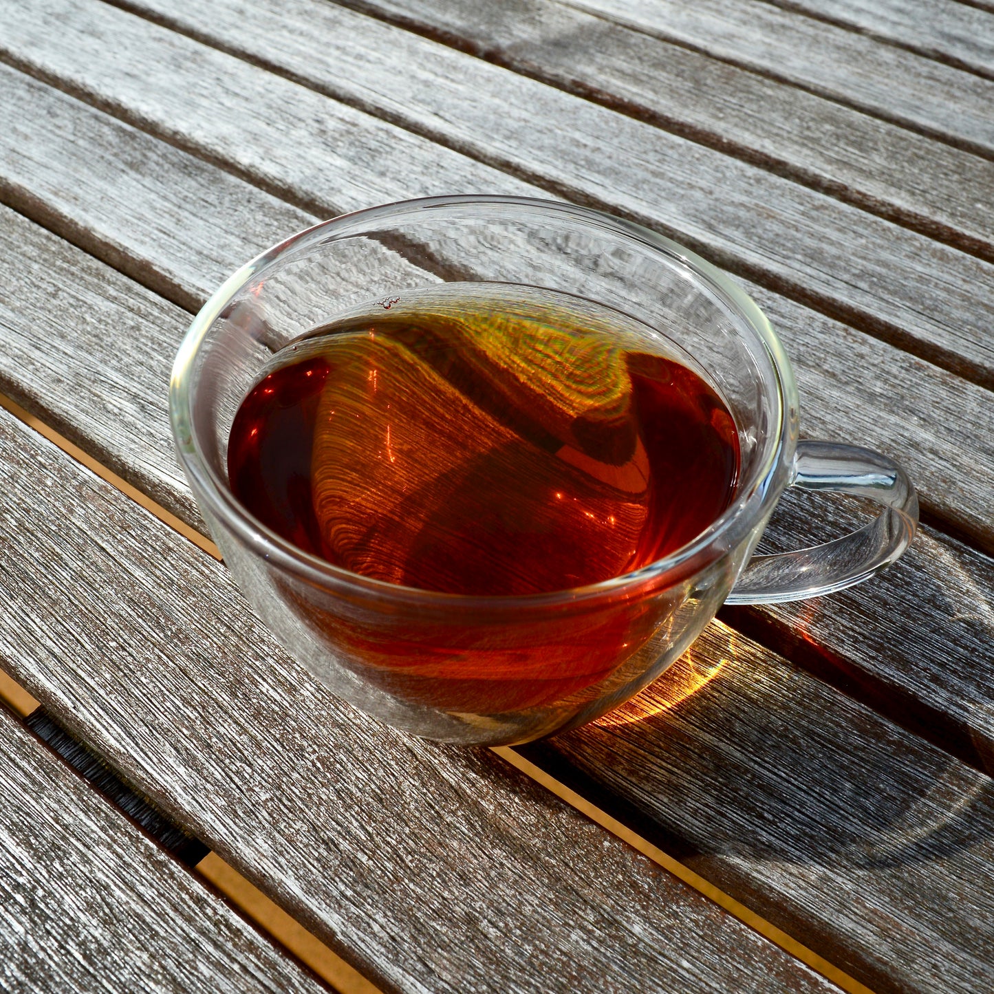 Anytime Black tea, decaf, steeped tea, decaffeinated black tea, on wooden table in glass tea cup