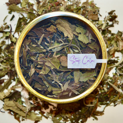 Bai Mu Dan top view White Tea 30 cups of tea size gold finish tin sitting on loose leaf tea that contains Chinese White Tea