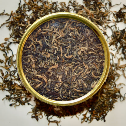 Golden Hour top view Black Tea 30 cups of tea size gold finish tin sitting on loose leaf tea that contains Nepalese black tea (Certified organic)