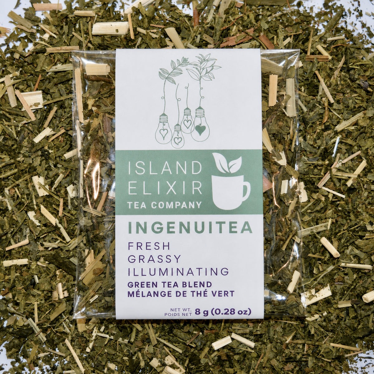 Ingenuitea Herbal Tea 4 cups of tea size compostable packaging sitting on loose leaf tea that contains Green tea*, lemongrass*, peppermint*, spearmint*.