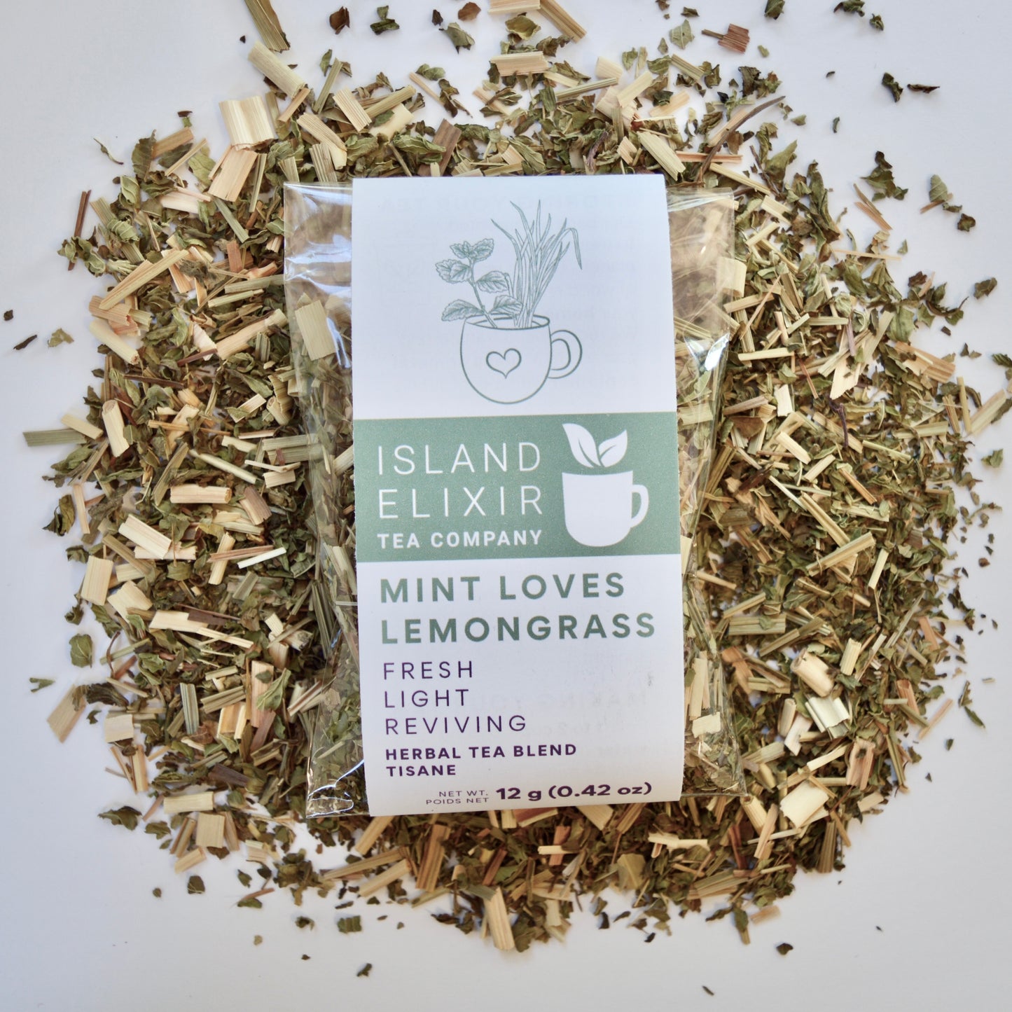 Mint loves lemongrass Herbal Tea 10 cups of tea size compostable packaging sitting on loose leaf tea that contains Lemongrass, peppermint, spearmint, lemon verbena