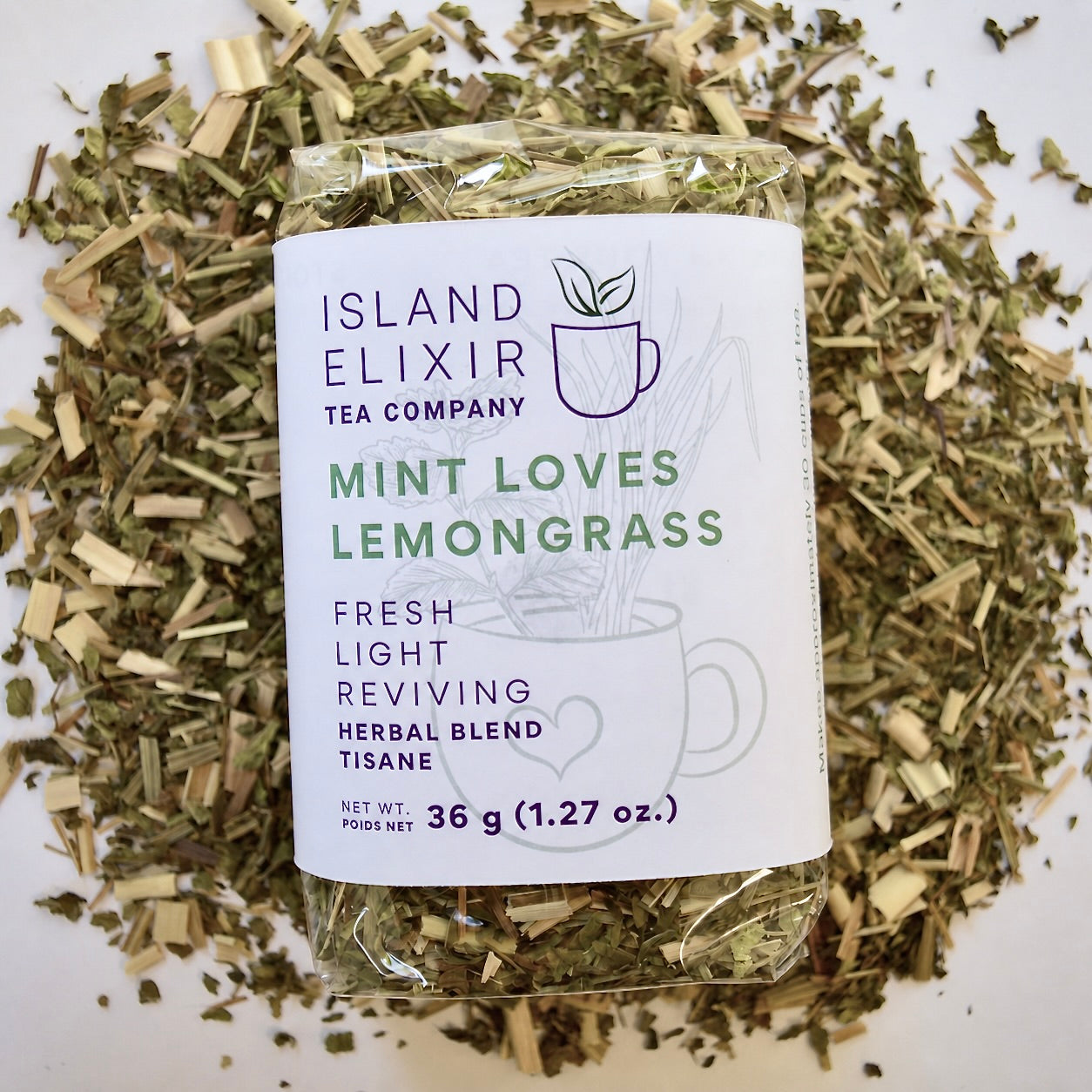 Mint loves lemongrass Herbal Tea 30 cups of tea size compostable packaging sitting on loose leaf tea that contains Lemongrass, peppermint, spearmint, lemon verbena