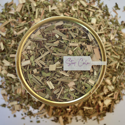 Mint loves lemongrass Herbal Tea 30 cups of tea size gold finish tin sitting on loose leaf tea that contains Lemongrass, peppermint, spearmint, lemon verbena
