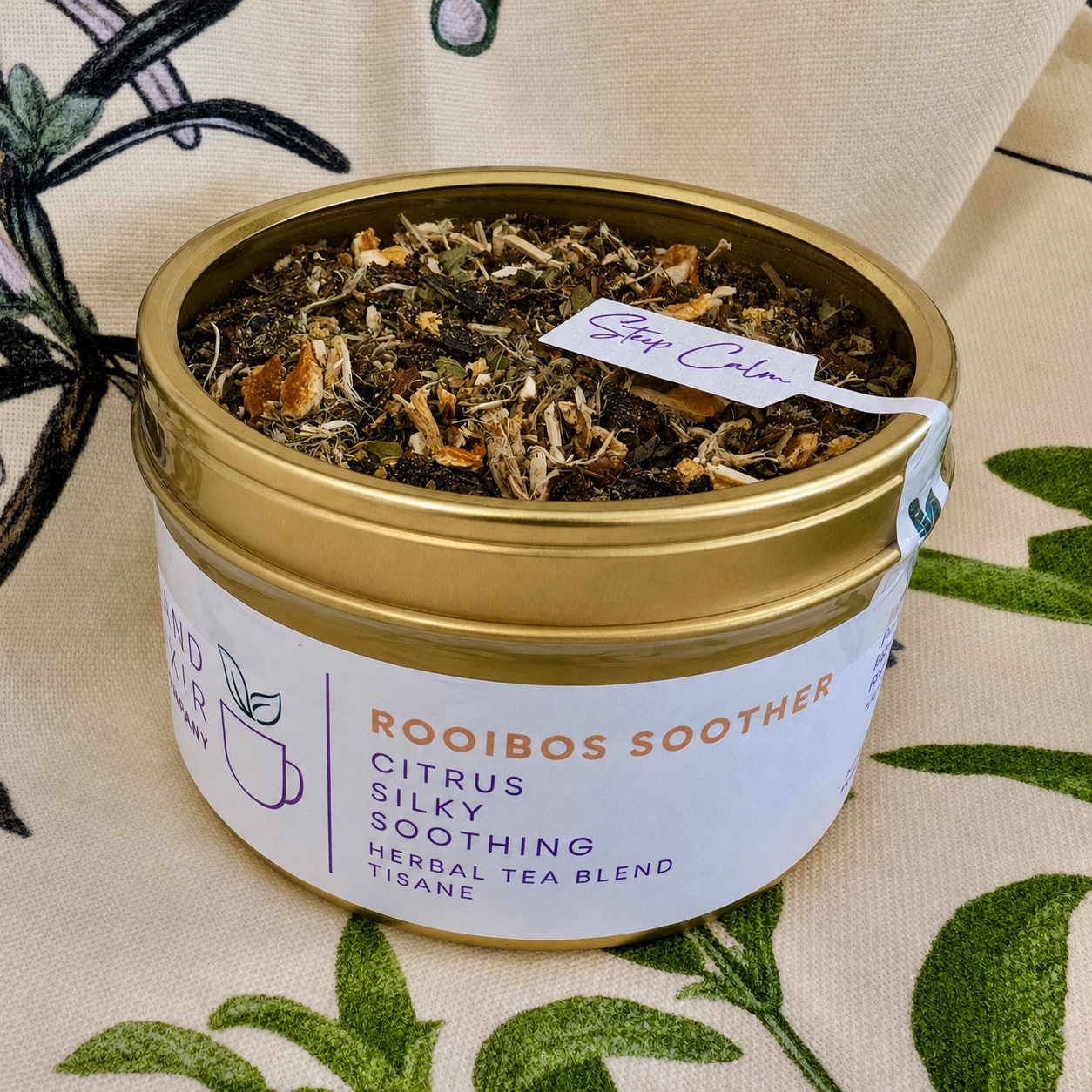 Rooibos Soother Herbal Tea 30 cups of tea size gold finish tin sitting on loose leaf tea that contains Marshmallow root, lemon, rooibos, elderflower, peppermint