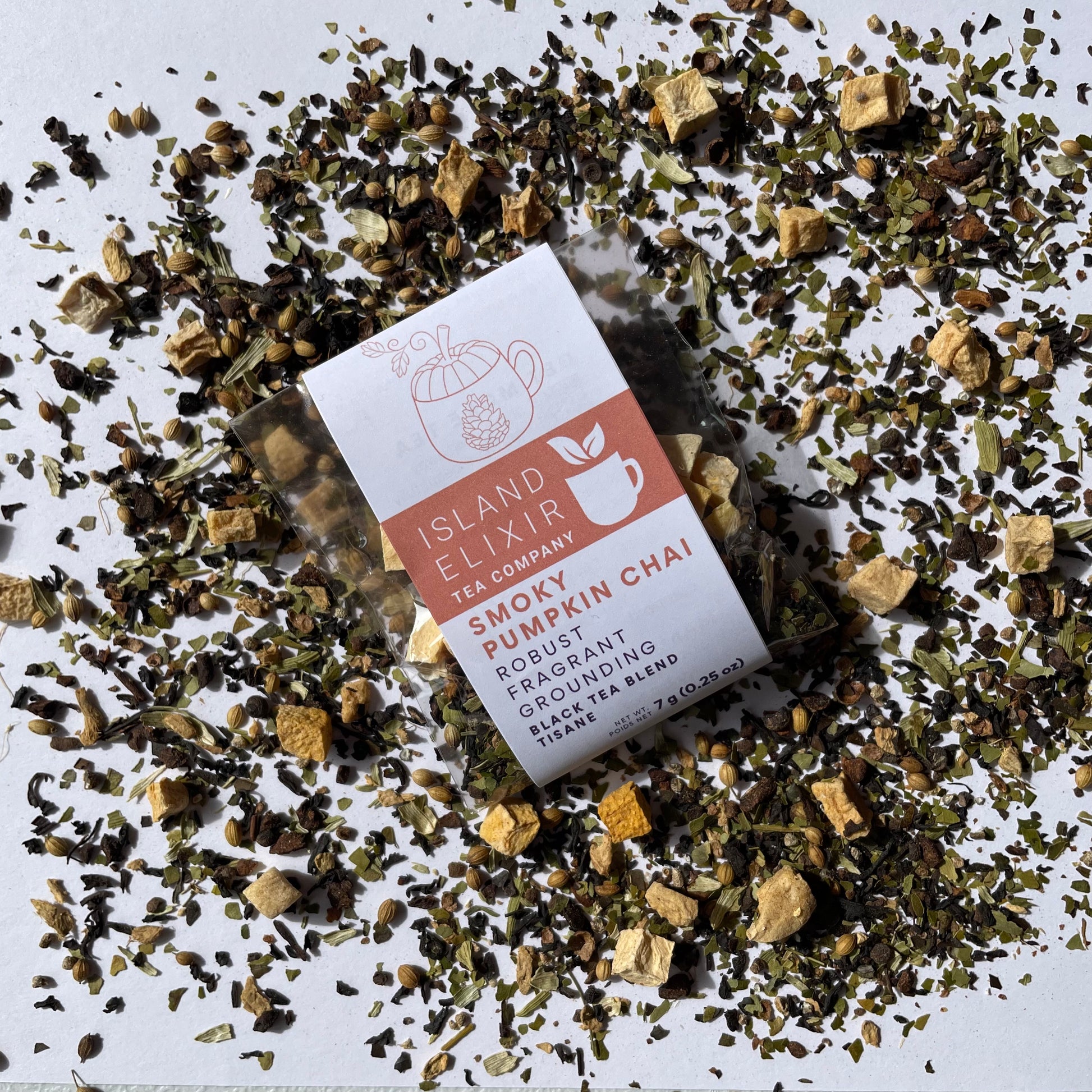 Island Elixir Smoky Pumpkin Chai tea 'Discover' size package surrounded by loose tea leaves on a white background