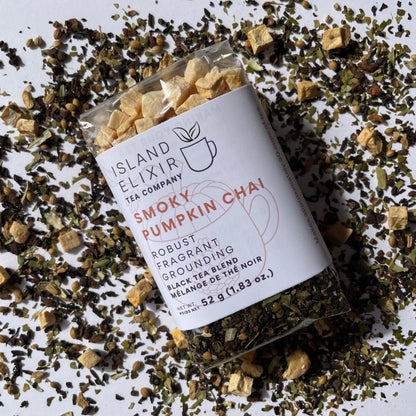 Island Elixir Smoky Pumpkin Chai tea 'Essential' size package surrounded by loose tea leaves on a white background