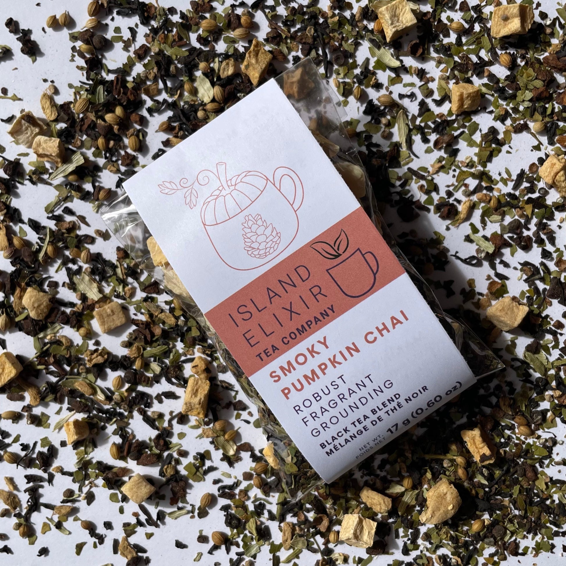 Island Elixir Smoky Pumpkin Chai tea 'Savour' size package surrounded by loose tea leaves on a white background