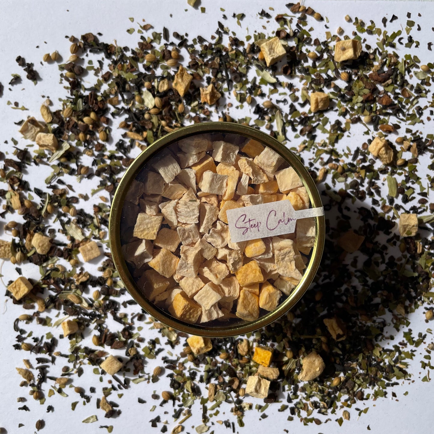 Island Elixir Smoky Pumpkin Chai tea 'Essential tin' size package viewed from the top surrounded by loose tea leaves on a white background