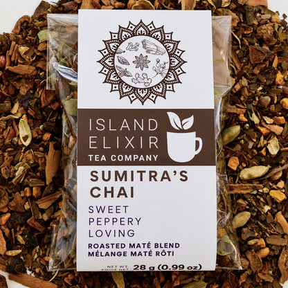 Sumitra's Chai Herbal Tea 10 cups of tea size compostable packaging sitting on loose leaf tea that contains Cinnamon*, Cardamom*, Rose hip*, Star anise*, Turmeric*, Roasted maté*, Clove*, Ginger*.