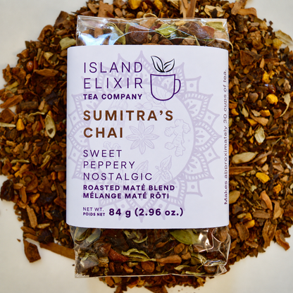 Sumitra's Chai Herbal Tea 30 cups of tea size compostable packaging sitting on loose leaf tea that contains Cinnamon*, Cardamom*, Rose hip*, Star anise*, Turmeric*, Roasted maté*, Clove*, Ginger*.