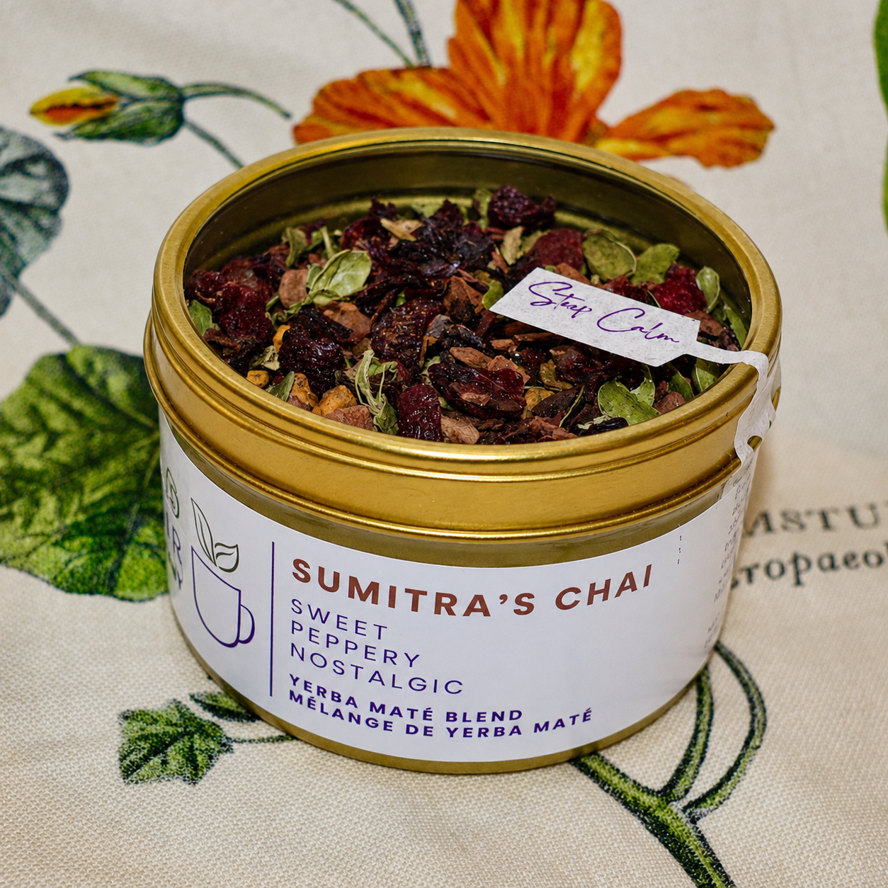 Sumitra's Chai Herbal Tea 30 cups of tea size gold finish tin sitting on loose leaf tea that contains Cinnamon*, Cardamom*, Rose hip*, Star anise*, Turmeric*, Roasted maté*, Clove*, Ginger*.
