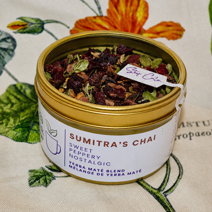 Sumitra's Chai Herbal Tea 30 cups of tea size gold finish tin sitting on loose leaf tea that contains Cinnamon*, Cardamom*, Rose hip*, Star anise*, Turmeric*, Roasted maté*, Clove*, Ginger*.
