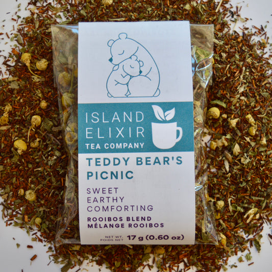 Teddy bear Picnic Herbal Tea 10 cups of tea size compostable packaging sitting on loose leaf tea that contains Rooibos, lemon balm, peppermint, chamomile