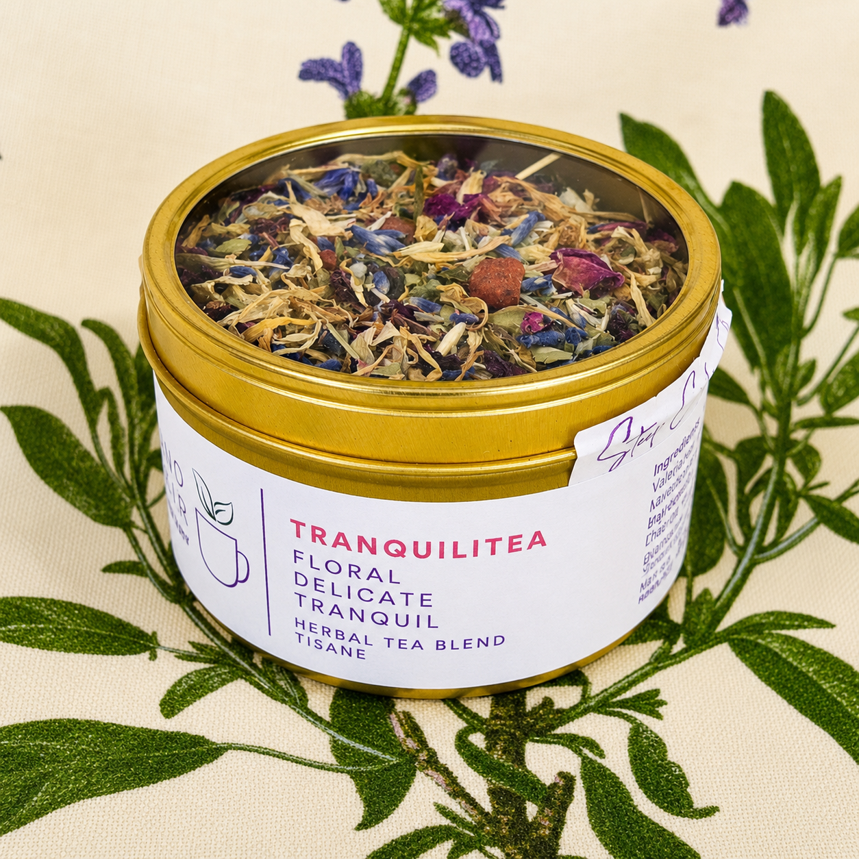 Tranquilitea Herbal Tea 30 cups of tea size gold finish tinsitting on loose leaf tea that contains Rose hip*, Lemon balm*, Lavender**, Oatstraw*, Marshmallow leaf*, Calendula*, Rose petals*.