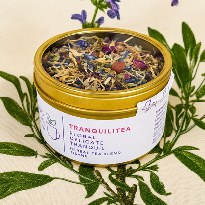 Tranquilitea Herbal Tea 30 cups of tea size gold finish tinsitting on loose leaf tea that contains Rose hip*, Lemon balm*, Lavender**, Oatstraw*, Marshmallow leaf*, Calendula*, Rose petals*.
