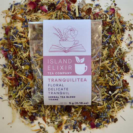 Tranquilitea Herbal Tea 4 cups of tea size compostable packaging sitting on loose leaf tea that contains Rose hip*, Lemon balm*, Lavender**, Oatstraw*, Marshmallow leaf*, Calendula*, Rose petals*. 