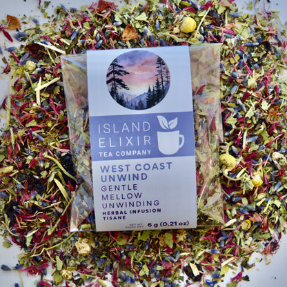 West Coast Unwind Herbal Tea 4 cups of tea size compostable packaging sitting on loose leaf tea that contains rose hip, lemon balm, lavender, marshmallow leaf, passion flower chamomile, red cornflower.